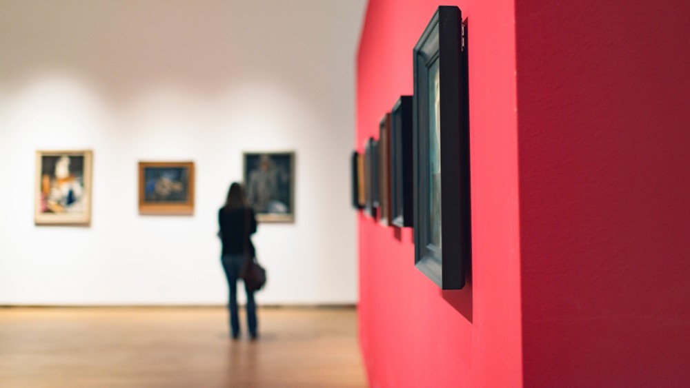 En person studerer malerier på et museum.